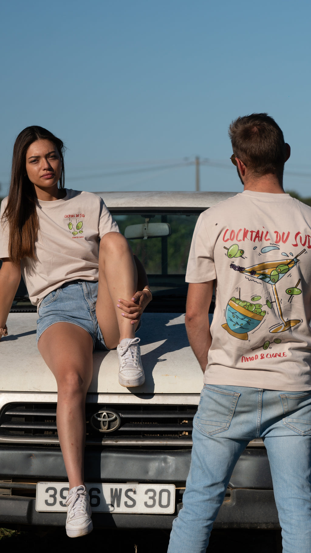 T-shirt blanc Amor & Cigale modèle Cocktail du Sud avec imprimé coloré dans le dos et sur le coeur, coupe unisexe, porté par un homme et une femme