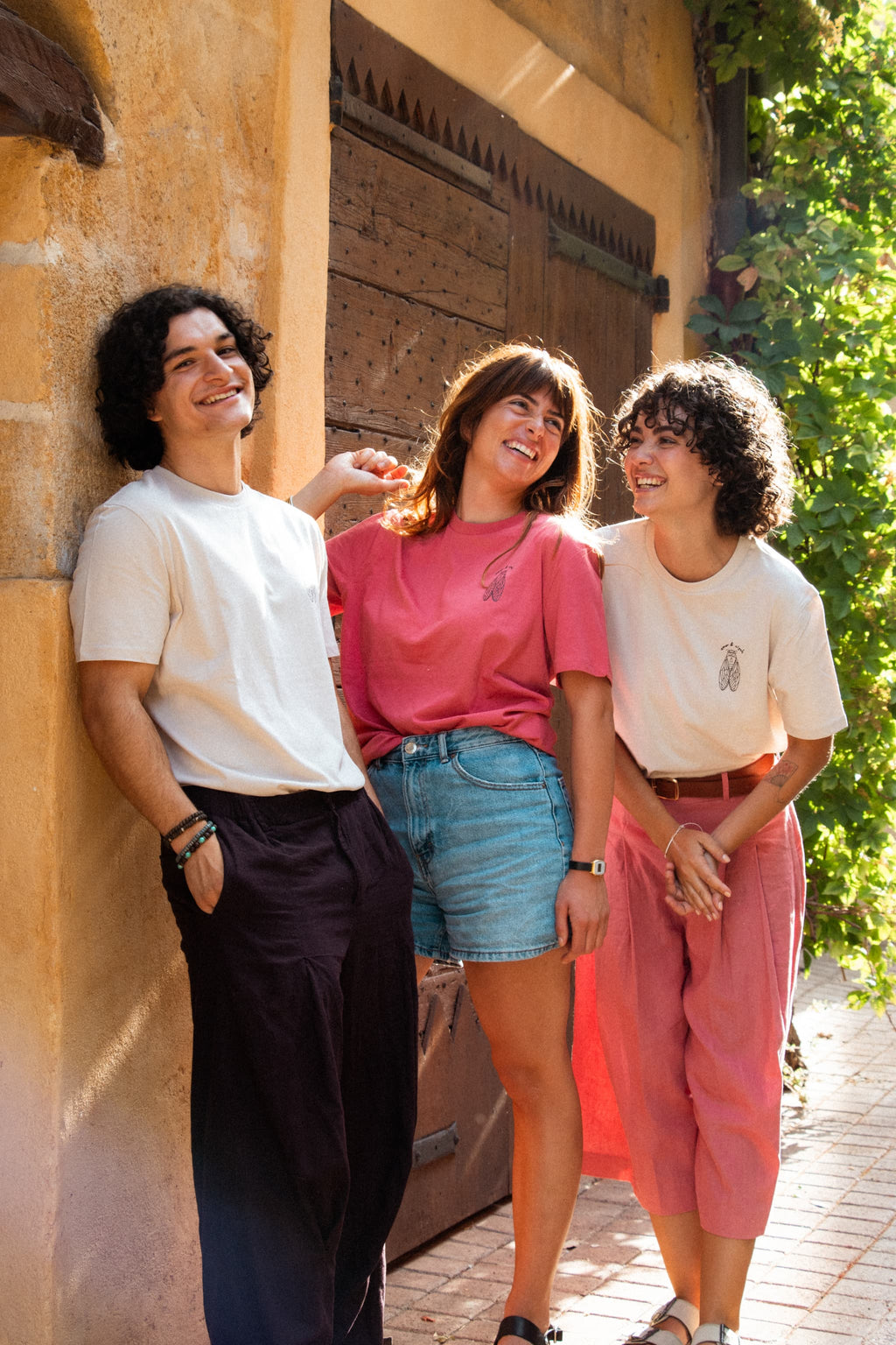 Trois mannequins portant le t-shirt Amor & Cigale modèle La Cigale : un homme et une femme en couleur Lin, une femme en couleur Rose Folk, logo sur le cœur, coupe unisexe